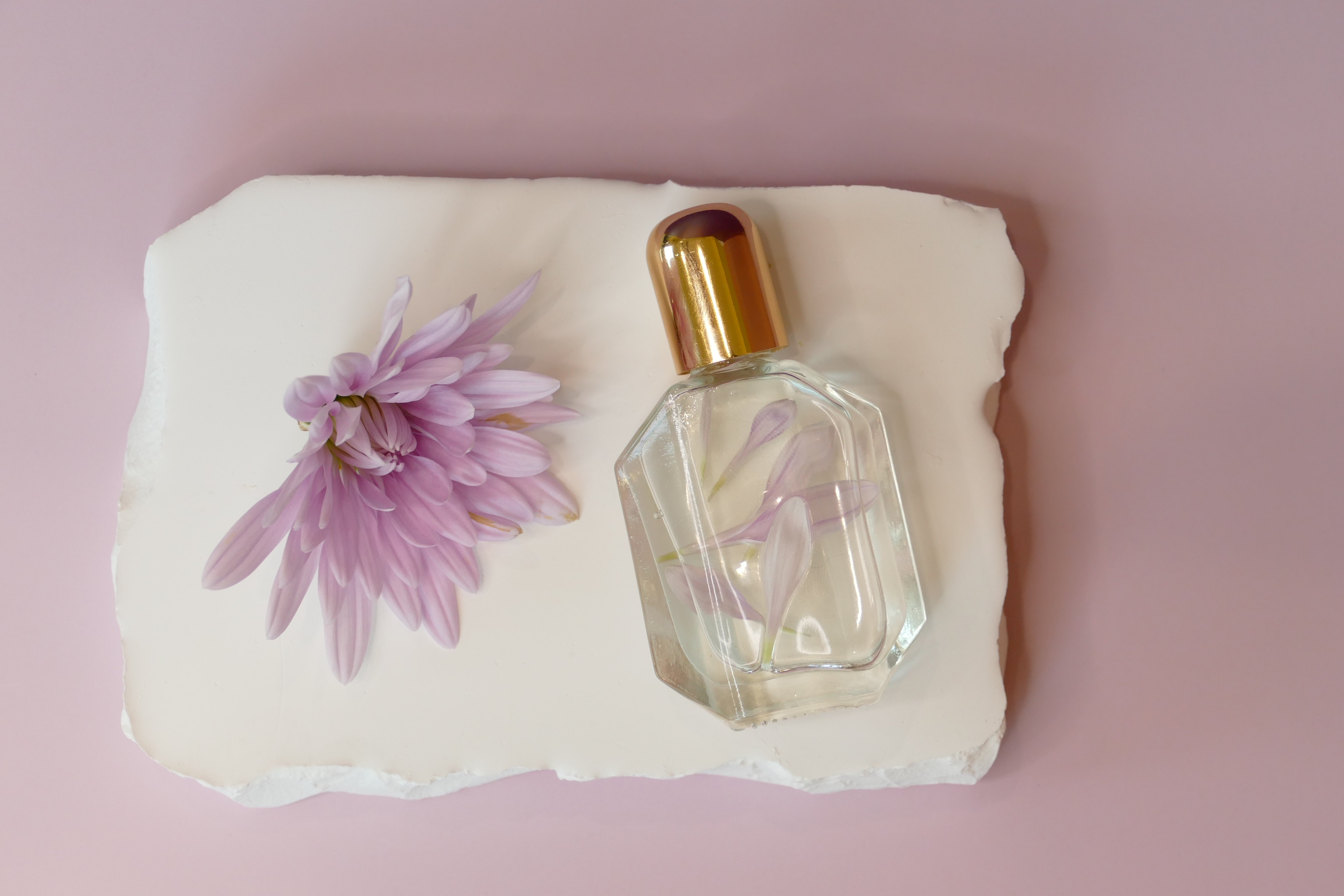 Purple background with purple flower and a glass roller