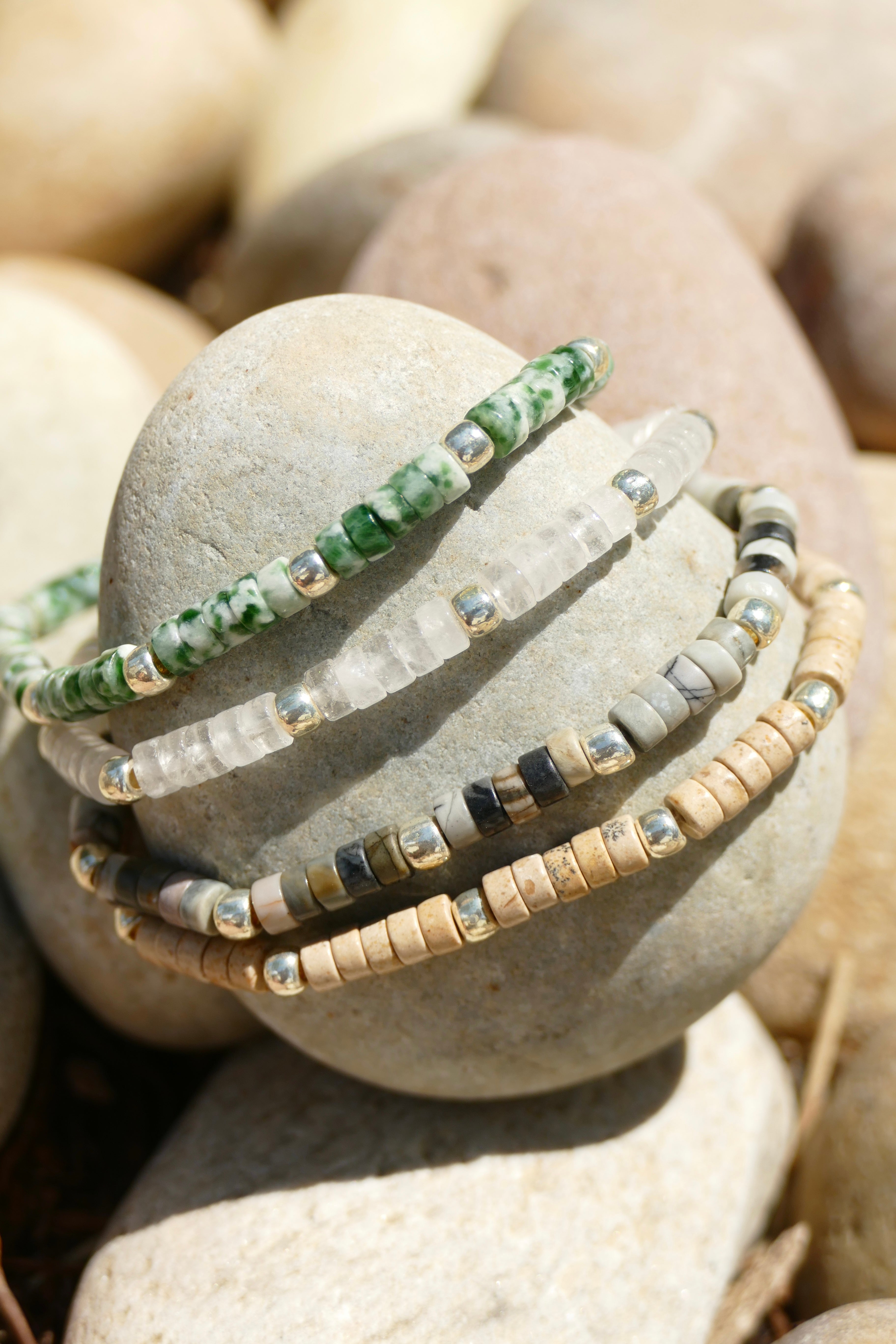 4 heishi bracelet stacked on a small rock